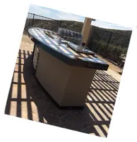 Curved outdoor kitchen island with dark counter on a sunny patio
