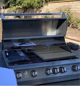 Open stainless steel built-in grill with a griddle plate on the grates
